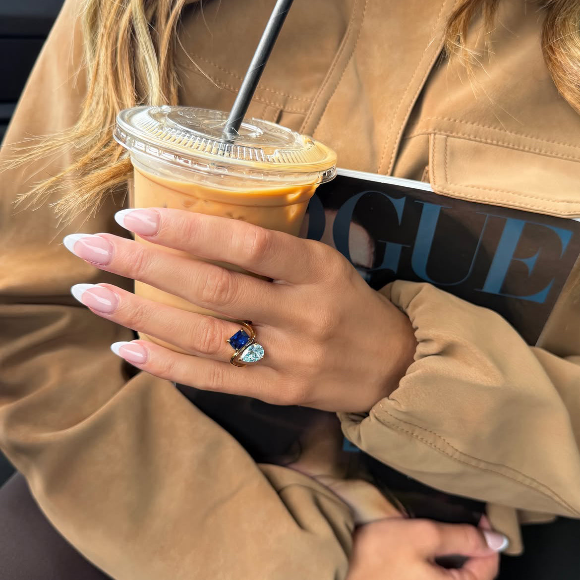 Toi et Moi ring with a blue stone, worn with an iced coffee and a magazine