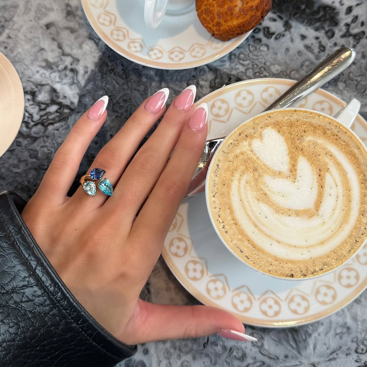 Ring with a blue stone, next to a latte
